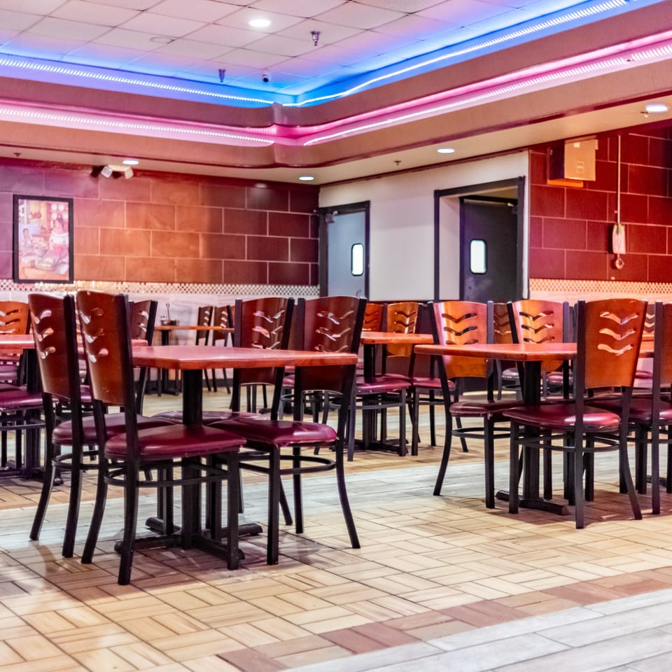 Empty dining room at Fajitas y Tequila with red tables, chairs, and neon lighting.