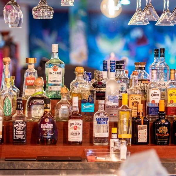 A well-stocked bar shelf with various liquor bottles, including tequila, vodka, and whiskey.